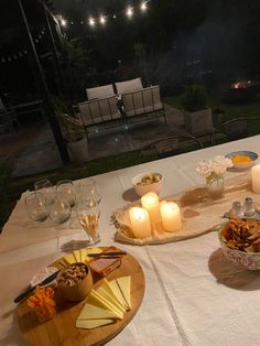 the table is set with food and candles for an outdoor dinner or party in the evening