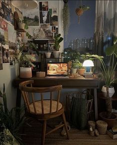 a desk with plants and pictures on the wall above it, along with a chair