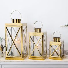 three gold lanterns sitting on top of a mantle