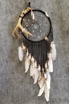 a black and white dream catcher with feathers hanging from it's side on the floor