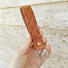 a hand holding a leather keychain with an arrow design on the front and back