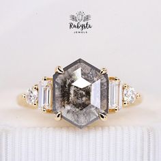 an image of a diamond ring with three stones on it's sides and the center stone surrounded by smaller diamonds