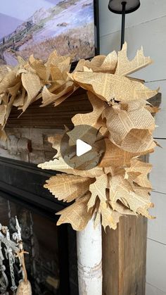 a wreath made out of burlocks on top of a white pillar in front of a fireplace