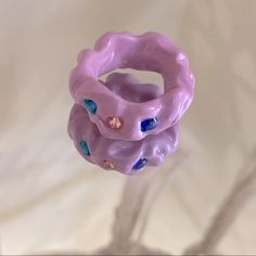 a purple ring with blue and pink beads on it's side, sitting on a white surface