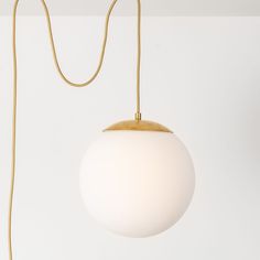 a white ball hanging from a gold colored cord on a light fixture in a room