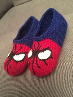 a pair of crocheted slippers with spiderman eyes