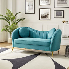 a blue couch sitting on top of a rug in a living room next to a potted plant