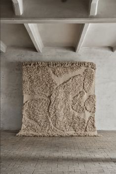 a large stone sculpture sitting on top of a brick floor next to a white wall