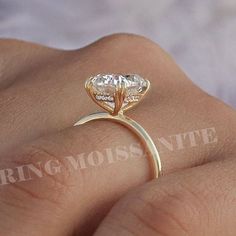 a woman's hand holding a ring with a heart shaped diamond on top of it