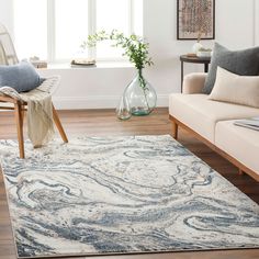 a living room area with couches, chairs and rugs on the hardwood floor