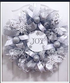 a christmas wreath with the word joy on it and ornaments hanging from the front door