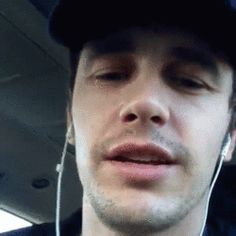 a man with ear buds on his ears wearing a baseball cap and listening to headphones