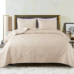 a bed with a beige comforter and pillows