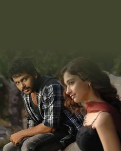 a man and woman sitting next to each other in front of some rocks with trees behind them