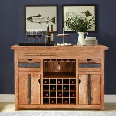 a table with wine bottles and glasses on it in front of two framed fish pictures