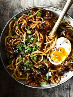 a bowl filled with noodles, meat and an egg on top of it next to chopsticks