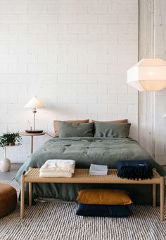 a bed sitting in a bedroom next to a lamp and table with folded towels on it