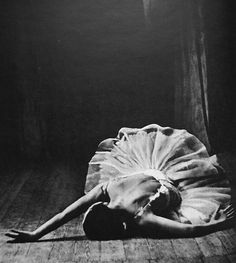 a black and white photo of a woman laying on the floor with her head down