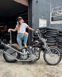 a woman sitting on top of a motorcycle next to a pile of tires and tubes