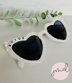 the bride sunglasses are decorated with pearls and black heart - shaped glasses, along with greenery