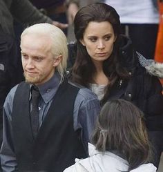 a man with white hair is talking to two other people