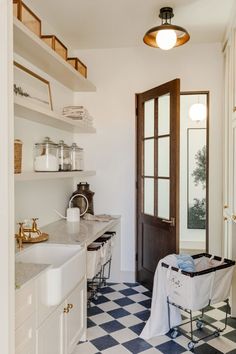 a kitchen with black and white checkered flooring next to an open front door