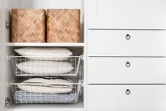 an organized closet with baskets and linens