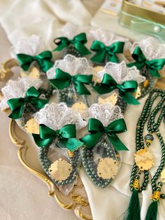 many green and white items are laying on a table with lace, beads, and bows