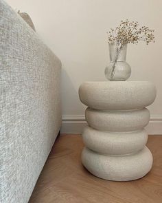 a stack of rocks next to a couch with a vase sitting on top of it