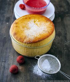 a cake with powdered sugar and raspberries next to it