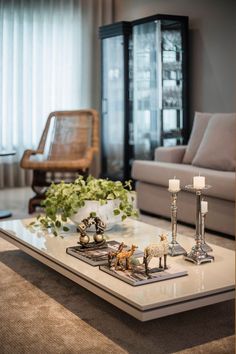 a table with candles and figurines on it in front of a couch, coffee table