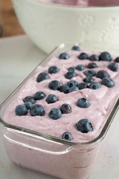 blueberries and cream in a glass dish on a table