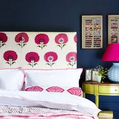 a bed with pink and white flowers on the headboard, next to a blue wall