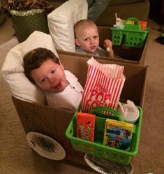 two young boys are sitting in boxes filled with toys