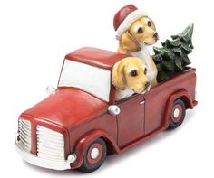 two dogs sitting in the back of a red truck with a christmas tree on top