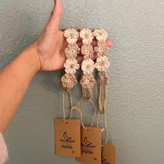 a hand is holding several small crocheted items in front of a blue wall