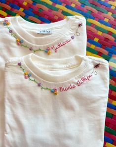 two white t - shirts with embroidered name and beaded neckline on colorful background