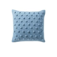 a light blue pillow with polka dots on the front and back, sitting against a white background