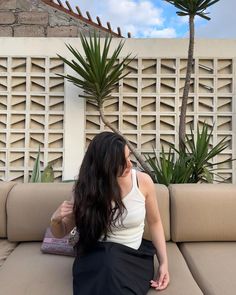 a woman sitting on top of a couch next to a palm tree