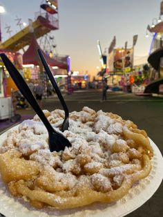 a powdered pastry on a paper plate at an amusement park