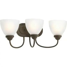 three light bathroom fixture with white glass shades on an aged bronze finish and dark wood accents