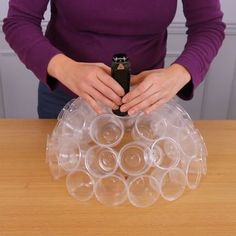 a woman holding a cell phone in front of a bunch of cups on a table