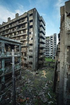 an old run down building with graffiti on the walls and in the foreground is a large number of other buildings