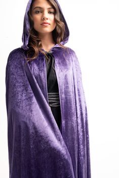 a woman wearing a purple cloak and black dress is standing in front of a white background