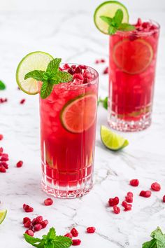 two glasses filled with pomegranate, lime and limeade garnished with mint