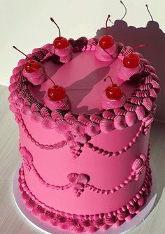 a pink cake with cherries on top