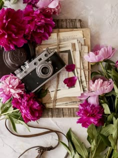 a camera and some pink flowers on a white tablecloth with an old fashioned camera