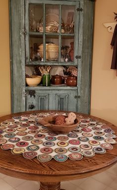 a wooden table topped with a bowl filled with food next to a hutch covered in plates