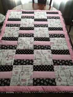 a pink and black quilted table runner sitting on top of a dining room table