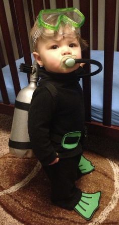 a small child wearing scuba gear and snorkels standing in front of a crib